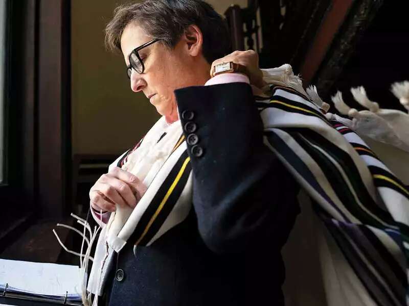 Rabbi Kleinbaum prepares for temple throwing tallit prayer shaw over shoulder