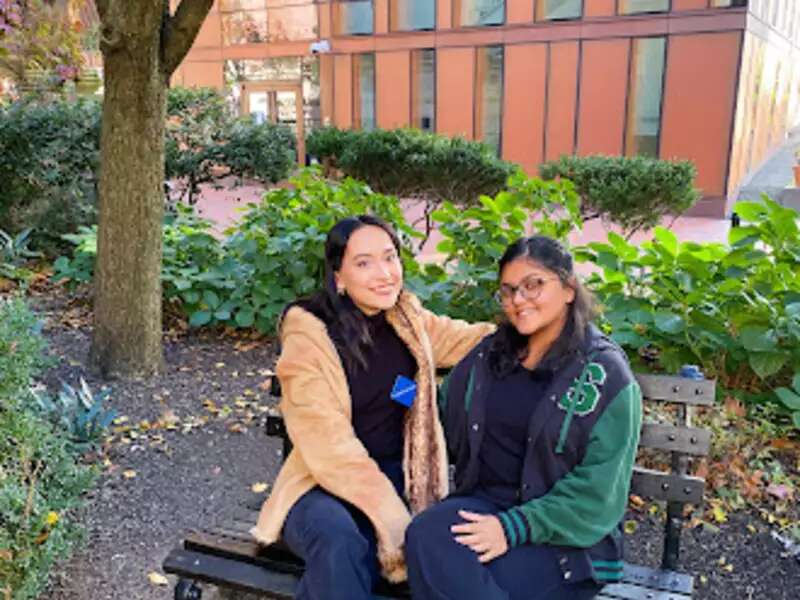 Two students sit on a bench on Barnard's campus