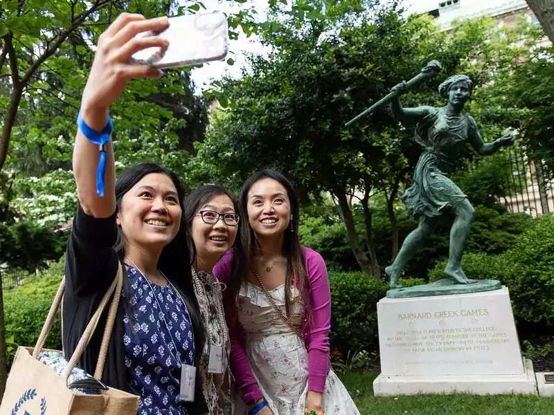Women pose with runner statue
