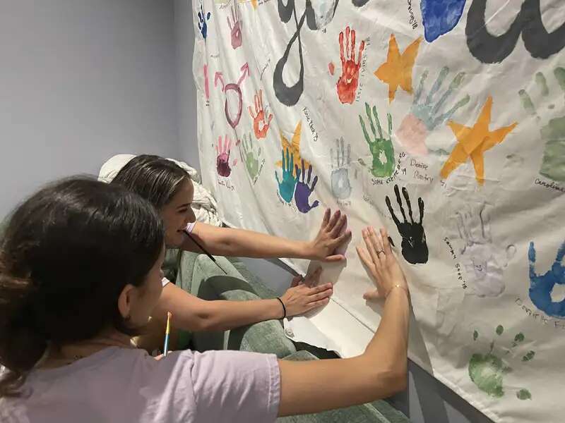 Students painting a sheet with their palm prints in the mental well-being suite.