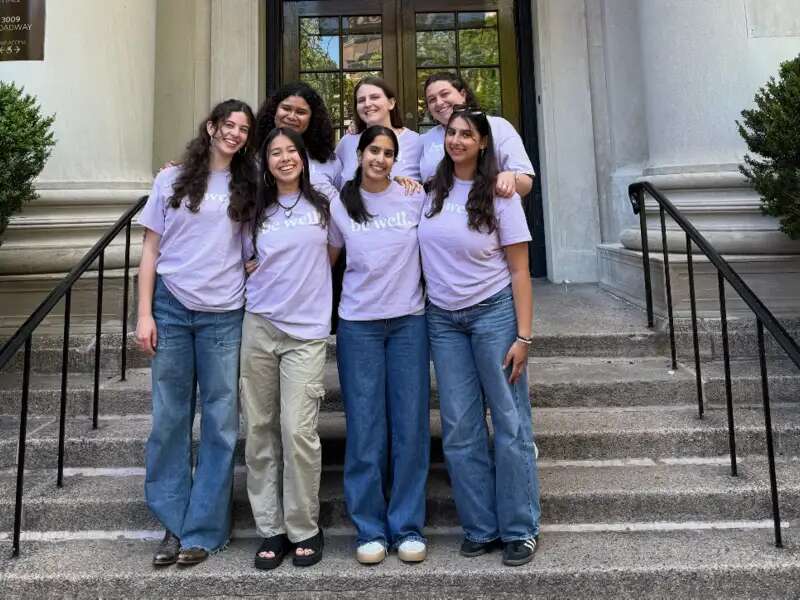 A group of Wellness Spot Peer Health Educators standing on the steps of Barnard hall in purple t-shirts