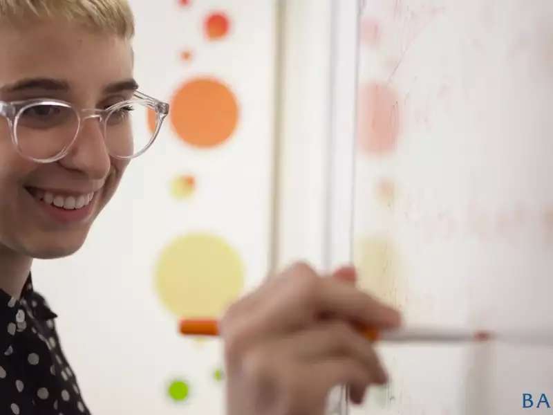 Close up of a white woman writing on a white board