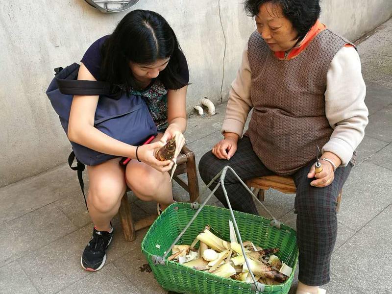 A student handles bamboo that an older woman has shucked