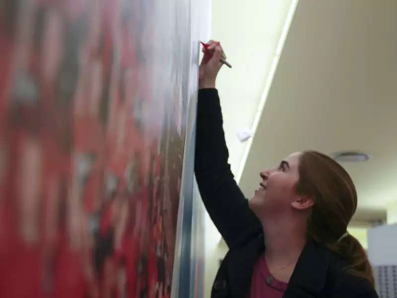 close up of a woman writing on a blackboard