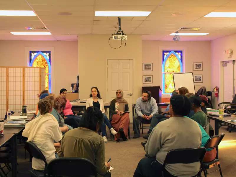 Group of people sitting in a circle on folding chairs