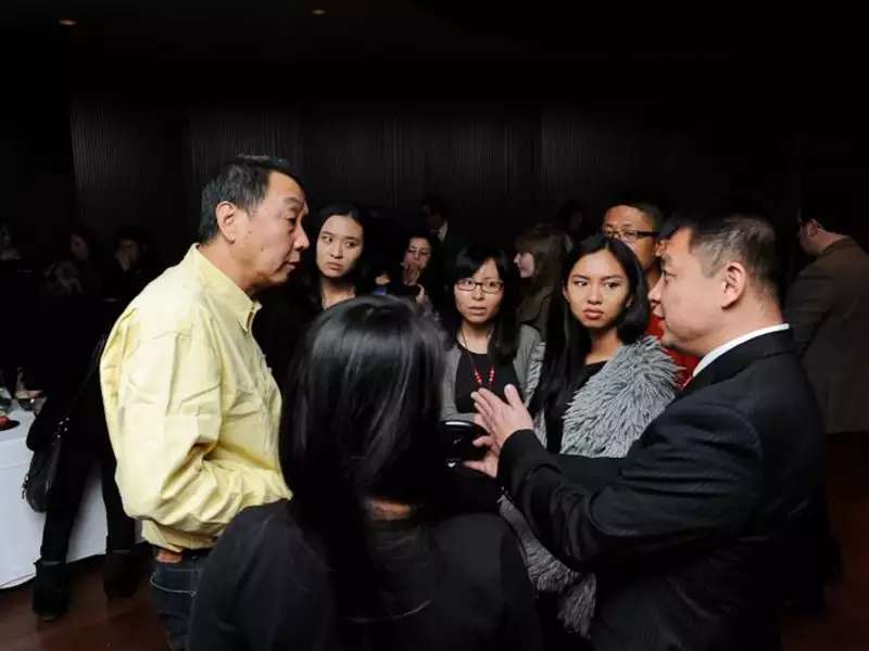 2 Asian men speak to each other with students listening