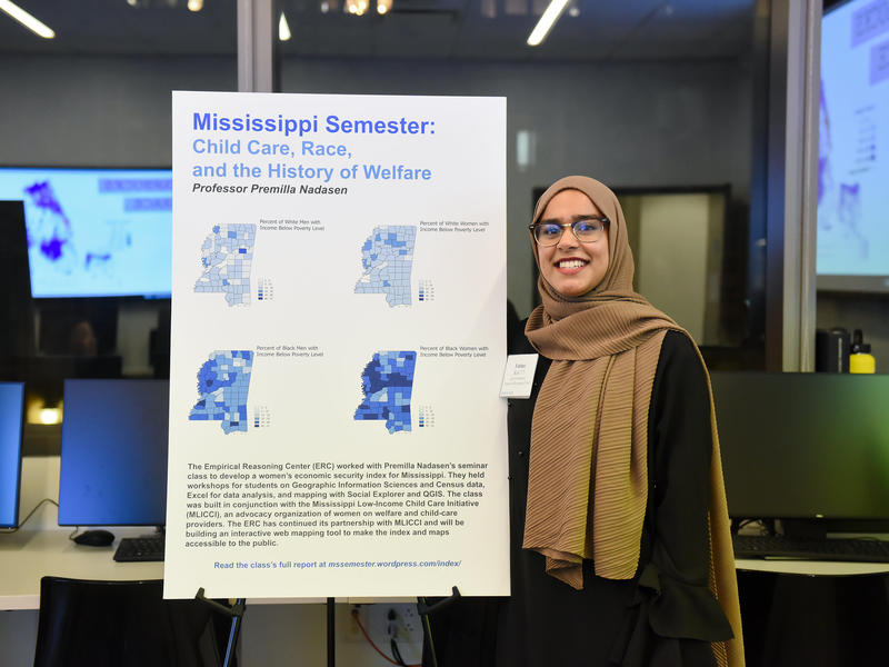 Woman wearing a hijab next to her poster presentation