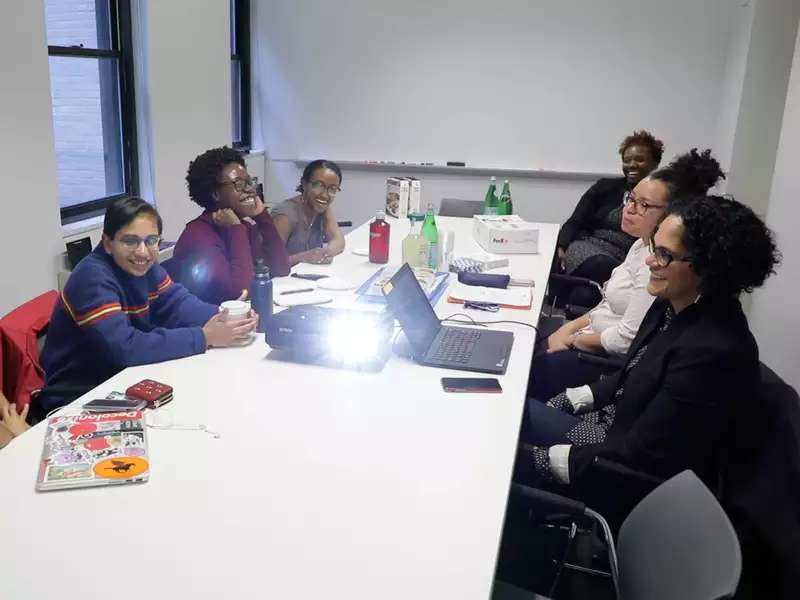 half a dozen women of color sit around a conference table