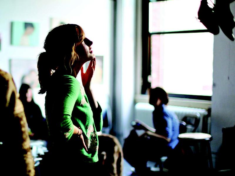 Young woman standing in a classroom, looking thoughtful