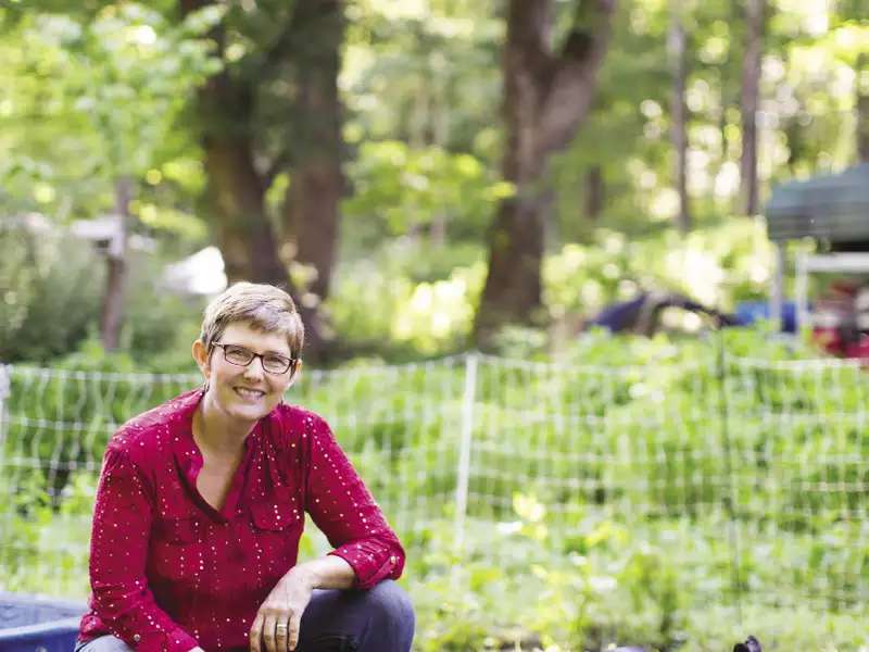 Crystal Cook Marshall ’94 in a field with black piglets
