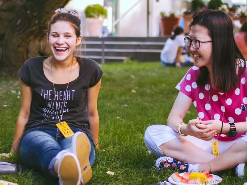 2 students on the grass, laughing